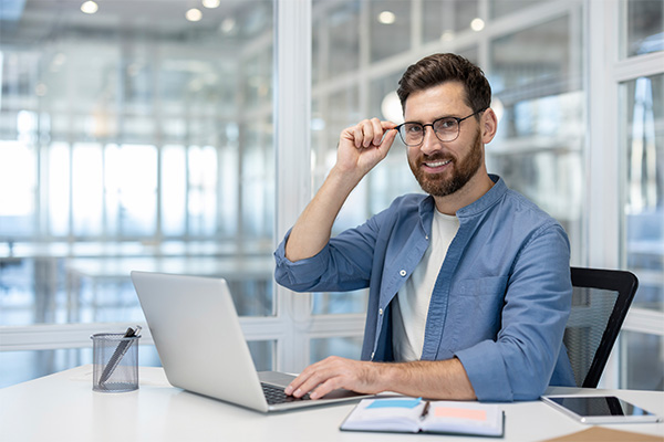 Foto: Lächelnde Mann mit Brille vor dem Notebook